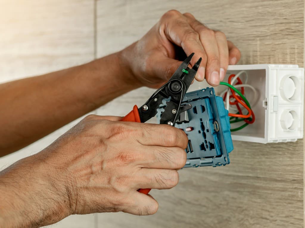 Licensed electrician installing wiring and outlets for commercial maintenance